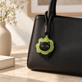 Grüner Katzen Taschenanhänger an schwarzer Handtasche