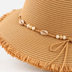 Detailansicht von Fransen Kordel und Muscheldetails des Boho Strohhuts