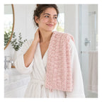 Frau mit einem hellrosa Macaron Series Gesichtstuch im Badezimmer