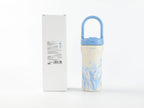 Florale Isolierflasche in Blau mit Verpackung auf weißem Hintergrund