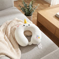 Cremeweißes Memory-Foam-Nackenkissen der Einhorn-Serie auf einem Sofa