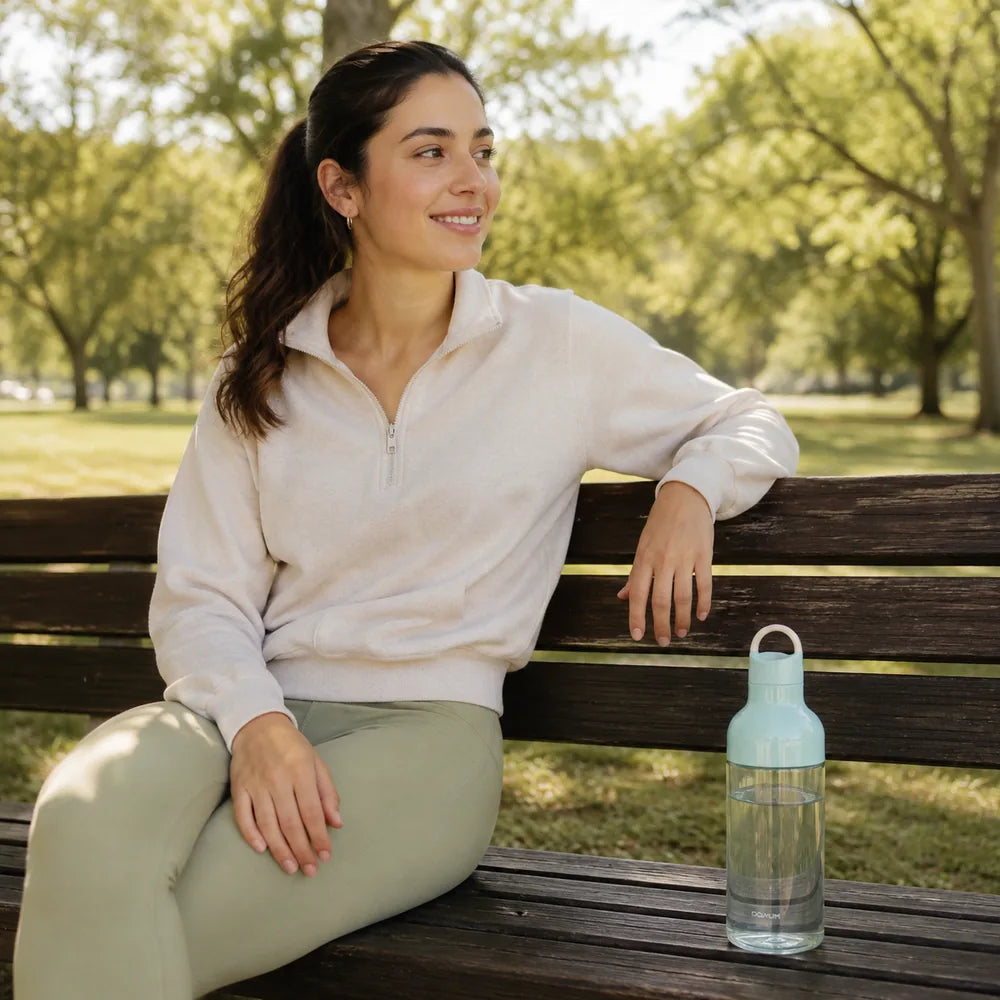 Frau im Park neben der blauen Macaron Trinkflasche 600 ml